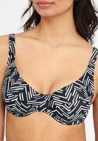 Zwart-wit gestreepte bh met teal accenten, met een gladde textuur, onderbedekking voor ondersteuning en verstelbare bandjes.