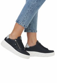 Schwarze Leder-Sneaker mit weißer Sohle, mit Schnürdesign und seitlichem Reißverschluss. Silberner Akzent an der Ferse und durchbrochene Details an der Seite.