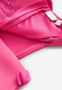 Heller pinker Badeanzug aus weichem Stoff, mit zarten Spitze-Details, sicherer Nähte und einem gerippten Akzent an der Seite.