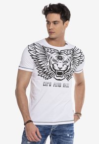 Weißes Baumwoll-T-Shirt mit einem großen schwarzen Tiger-Design mit Flügeln, rundem Ausschnitt und kurzen Ärmeln. Textdruck unter dem Design.