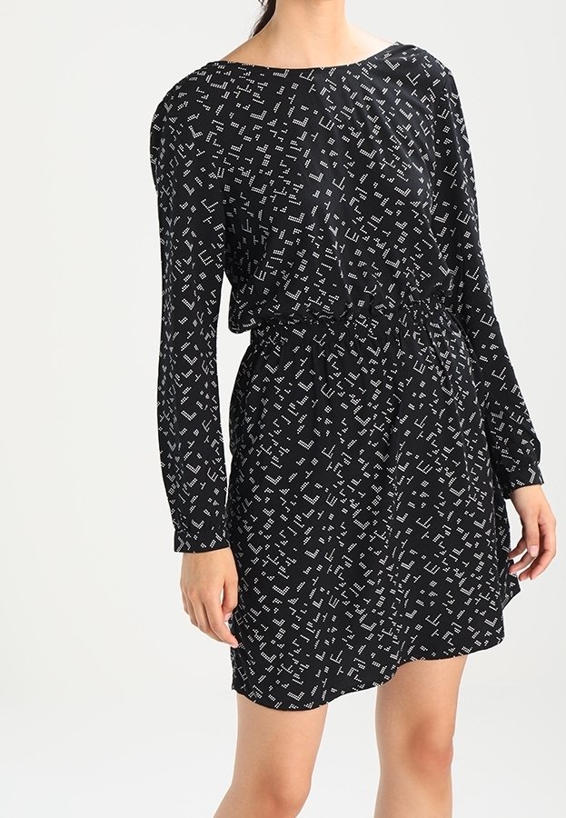 Czarna sukienka z długimi rękawami, ozdobiona białym geometrycznym wzorem. Elastyczna talia i luźny krój z dekoltem w łódkę.