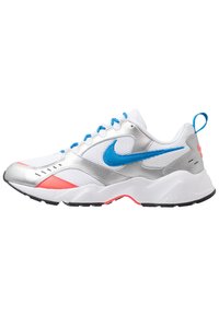 Baskets sportives Nike présentant un mélange de mesh blanc, d'accents argentés et de détails bleu vif. Elles ont une semelle blanche épaisse avec des reflets roses.