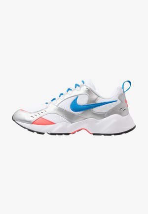 Baskets sportives Nike présentant un mélange de mesh blanc, d'accents argentés et de détails bleu vif. Elles ont une semelle blanche épaisse avec des reflets roses.
