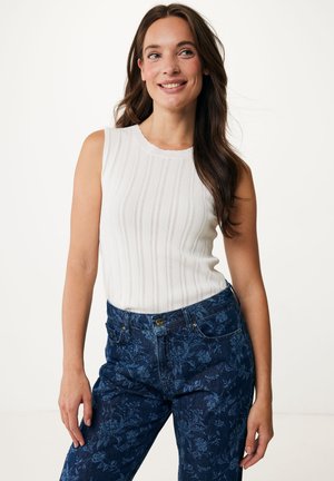 Haut sans manches blanc à côtes avec un col festonné, associé à un jean foncé à motifs floraux. Texture lisse et coupe ajustée.