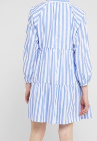 Blau-weißer gestreifter Hemdkleid mit gerafftem Bund, langen Ärmeln und ausgestelltem Rock. Aus leichtem Stoff gefertigt.