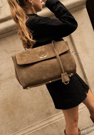 Borsa in suede color taupe con pattina pieghevole, hardware dorato e tracolla, dotata di accenti metallici e finitura testurizzata.