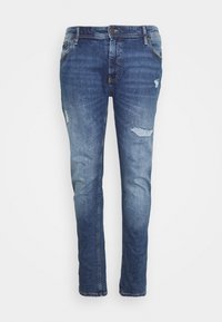 Jean en denim bleu avec une coupe slim, présentant un lavage délavé, des détails usés et cinq poches. Fermeture sécurisée par bouton et zip.