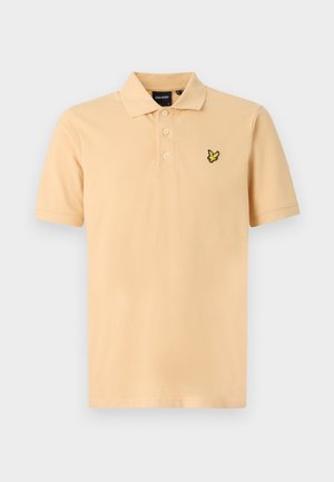 Cămașă polo în piersică deschisă cu un guler cu trei nasturi. Prezintă un logo brodat în negru și galben pe partea stângă a pieptului. Mâneci scurte, croială clasică.