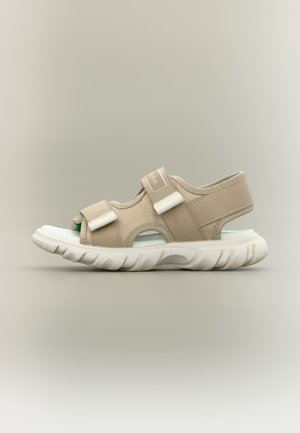 Beige open-toe sandal with adjustable straps and thick white sole, side view on neutral background.