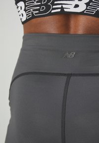 Szürke sport leggings sima textúrával, finom New Balance logóval és kontrasztos fekete varrással.