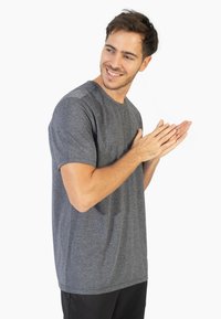 Grijze korte mouwen shirt van een gestructureerde stof, met een ontspannen pasvorm en ronde halslijn. Gecombineerd met zwarte broek.