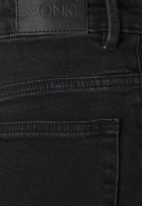 Svarta jeans i denim med en läderetikett där "MONKI" är präglat. Inkluderar två framfickor och subtila sömnadsdetaljer.