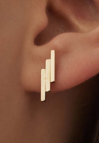 Boucles d'oreilles en métal doré comportant trois barres rectangulaires ascendantes avec une finition polie, fixées au lobe de l'oreille, mettant en valeur un design géométrique.