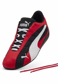 Zapatillas de carrera Puma con parte superior de ante rojo y malla negra, detalles en blanco y cordones rojos. Diseño estilizado con una forma curva y un acabado texturizado.