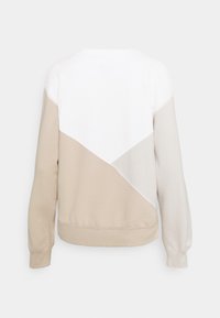 Sudadera beige y crema con un diseño de color bloque y un patrón geométrico. Tejido texturizado con puños y dobladillo acanalados.