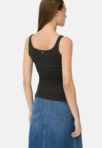 Sort tanktop med rund halsudskæring, sømløse skuldre og en lille detalje på ryggen, parret med en denimnederdel.