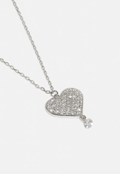 Srebrny naszyjnik w kształcie serca z powierzchnią zdobioną małymi, przezroczystymi kamieniami, z pojedynczym zwisającym akcentem w postaci przezroczystego dżetu.