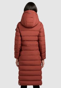 Lang, hættepuffet frakke i rustfarve. Har quiltet design, figursyet talje og lige kant. Glat tekstur med ribbede manchetter.