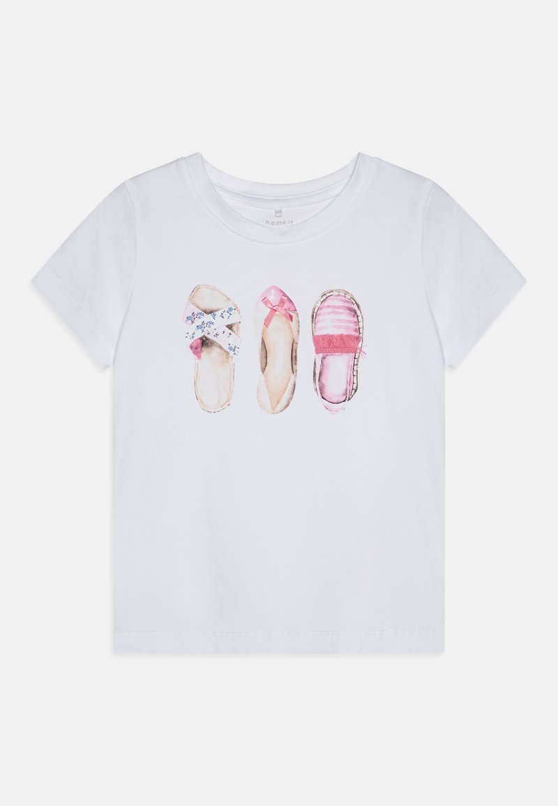 T-shirt branco com um design impresso de três pares de sapatos: com padrão floral, strappy rosa e estilo trançado com detalhes em rosa.