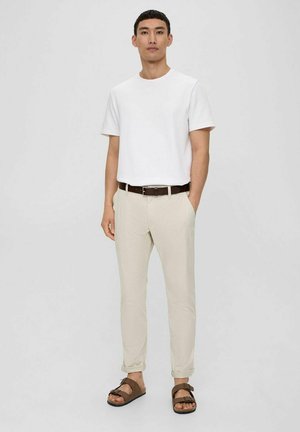 Weißes kurzärmeliges Baumwoll-T-Shirt, beige Slim-Fit-Hosen, brauer Ledergürtel und braune Sandalen mit Schnallen-Details. Einfaches Design und weiche Textur.