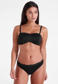 Czarny komplet bielizny typu bandeau z gładkiego, elastycznego materiału; posiada cienkie regulowane ramiączka oraz falbanę z koronki z falbanką na majtkach.