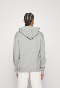 Sweat à capuche gris à manches longues, avec poignets et ourlet côtelés, doté d'un cordon de serrage. Texture douce, design décontracté.