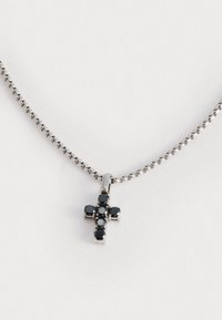 Collana d'argento con ciondolo a forma di croce decorata con pietre nere. La catena è delicata e presenta un design a maglie semplice, mettendo in risalto i dettagli del ciondolo.