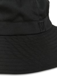 Svart bucket hat i ribbat tyg, med en bred skärm och sömnadsdetaljer. Inkluderar en subtil logotyp på bandet.