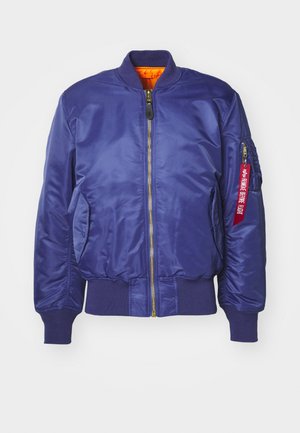 Veste bomber bleu marine en matériau satiné. Présente une fermeture éclair dorée, des poignets côtelés et une doublure orange avec une étiquette en tissu rouge sur la manche.
