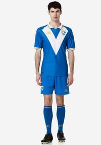 Blauw voetbaltenue met een wit chevrondesign, gouden accenten en logo op de borst. Inclusief bijpassende shorts en blauwe sokken.