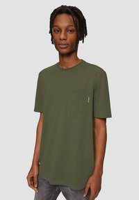 Olijfgroen T-shirt met korte mouwen van katoen, met een ronde hals en een borstzak. Beschikt over een comfortabele pasvorm en een zachte textuur.