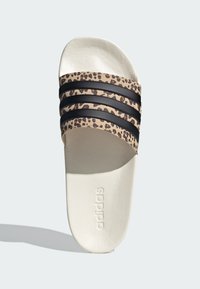 Adidas pantofle s béžovým svrškem se vzorem leopardí kůže, třemi černými pruhy a texturovanou bílou podrážkou. Logo značky vyražené na stélce.