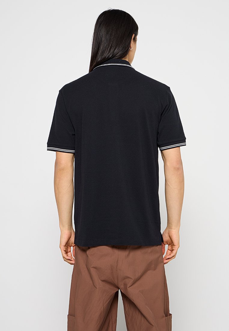 Schwarzes Polo-Shirt mit kurzen Ärmeln, schlanker Schnitt und weißen Streifenakzenten am Kragen und an den Ärmelabschlüssen. Glatte Baumwollstruktur.