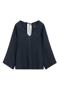 Blouse bleu foncé à manches longues avec fines rayures verticales blanches, manches larges, col en V et fermeture à nouer dans le dos.