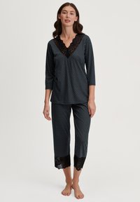 Set di pigiama nero con pois, caratterizzato da un collo a V con profilo in pizzo, maniche a tre quarti e pantaloni cropped con dettagli in pizzo all'orlo.