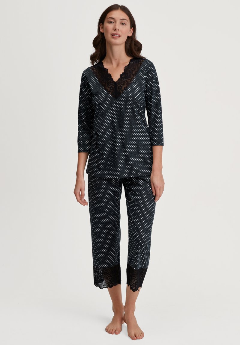 Set di pigiama nero con pois, caratterizzato da un collo a V con profilo in pizzo, maniche a tre quarti e pantaloni cropped con dettagli in pizzo all'orlo.