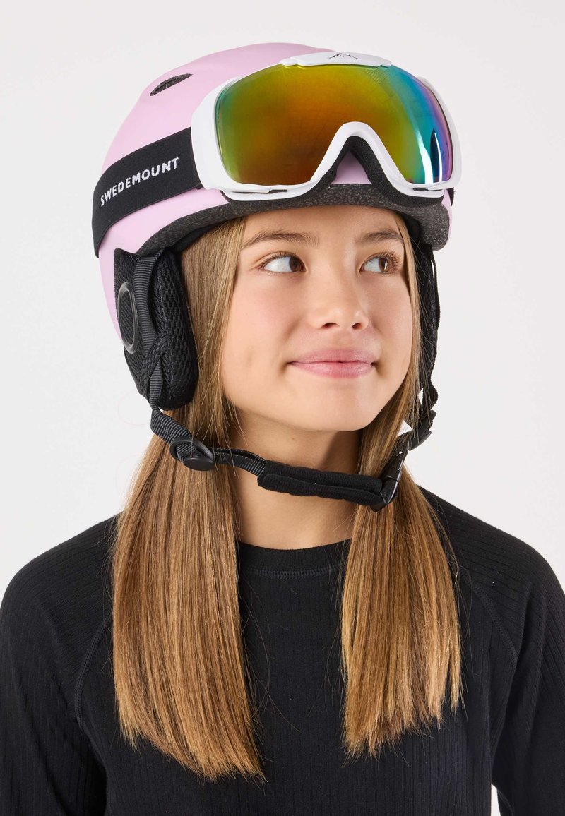 Pink ski helmet with black ear pads and strap labeled "SWEDMOUNT." White ski goggles with a reflective lens positioned above the forehead.