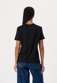 Černé tričko s krátkým rukávem a kulatým výstřihem, vyrobené z měkké bavlny. Tkanina má hladkou texturu, volný střih a jednoduchý design.