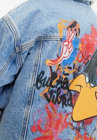 Džínová bunda s barevným graffiti stylem, včetně výrazných barev, abstraktních tvarů a textových detailů. Doplněná hravými grafikami.