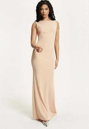 Form-fitting, sleeveless, blush gown with a square neckline; smooth texture and full-length design. Paired with metallic pointed shoes.