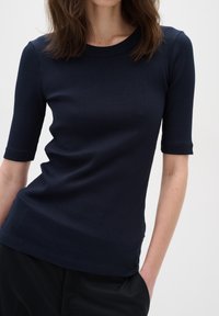 Námořnický proužkovaný top s krátkým rukávem a kulatým výstřihem. Má přiléhavý střih a měkkou texturu. Je stylizován s jemným zakončením lemu.