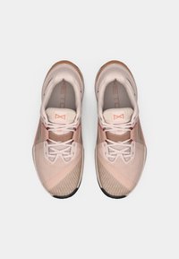 Lichtroze sportieve schoenen met een ademende bovenlaag van mesh, platte veters, gestructureerde patronen en een rubberen zool met bruine accenten.