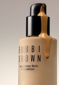 Bobbi Brown Weightless Skin Foundation i en frostet glassflaske med svart pumpe. Foundationen har en tan-farge som glir jevnt fra dysen.