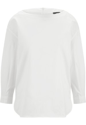 Hvid bluse med lange ærmer, rund halsudskæring og let buet kant, vist mod en ensfarvet baggrund.