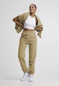 Lys brun mønstrede bukser med en teksturert stoff, elastisk liv og oppbrettede ankler, kombinert med en hvit crop topp og hvite sneakers.
