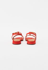 Sandali in suede rosso con più cinghie, tacco piatto e soletta testurizzata. Presentano una fibbia regolabile per una vestibilità sicura.