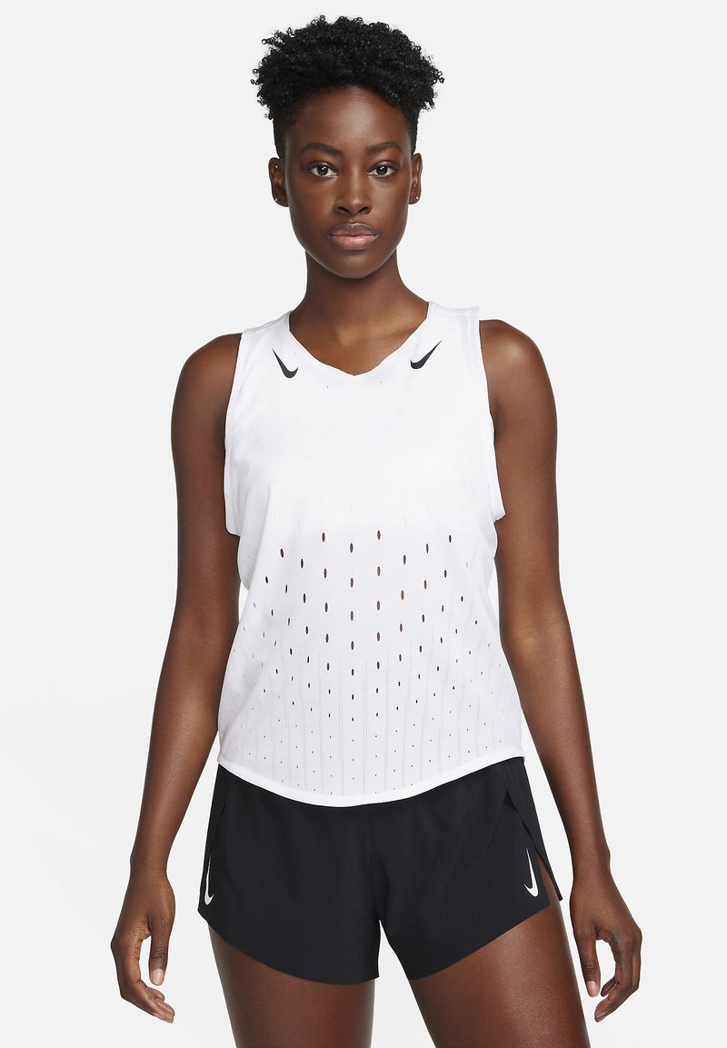 Débardeur de sport blanc sans manches avec un design perforé et des accents noirs. Associé à un short noir arborant un petit logo blanc.