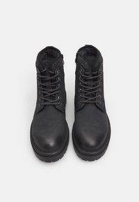 Botas de cuero negro hasta el tobillo con interior texturizado, punta redonda, ojales de metal y cordones en contraste. Suela de goma gruesa para mayor durabilidad.