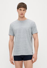 Γκρι κοντομάνικη μπλούζα με στρογγυλή λαιμόκοψη από υφασμάτινο υλικό, σε συνδυασμό με σκούρο μπλε σορτς, με μικρό λογότυπο στο τελείωμα.