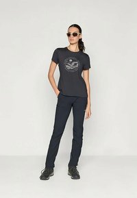 Meeste tumehall T-särk graafilise trükiga ja lühikeste varrukatega, koos laevadega sobivate tumedate siniste pükstega ja mustade matkasaabastega.